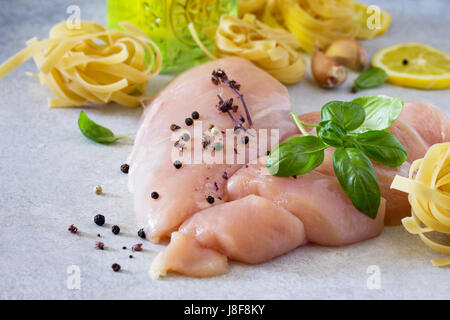 Matières premières fraîches filet de poulet avec le citron, les épices et le basilic sur la table de la cuisine. Arrière-plan de l'alimentation. Copier l'espace. Banque D'Images