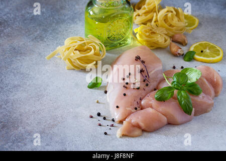 Matières premières fraîches filet de poulet avec le citron, les épices et le basilic sur la table de la cuisine. Arrière-plan de l'alimentation. Copier l'espace. Banque D'Images
