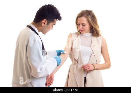 Jeune médecin beau avec des cheveux noirs en robe blanche avec stéthoscope et gants bleu faire une injection de très jolie femme aux longs cheveux bruns dans Banque D'Images