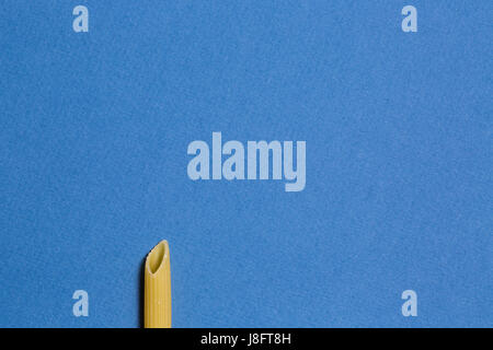 Pâtes penne unique tube sur fond bleu. Photo conceptuelle abstraite avec copie espace. Banque D'Images