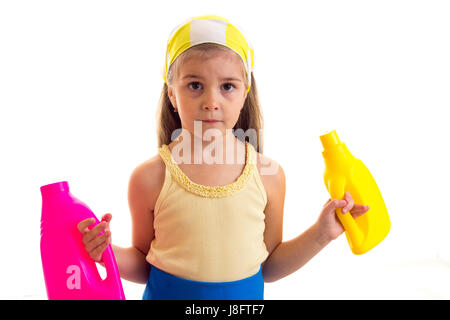 Triste petite fille avec de longs cheveux châtains en chemise jaune et tablier bleu avec mouchoir jaune tenue rose et jaune bouteilles sur fond blanc dans le stu Banque D'Images