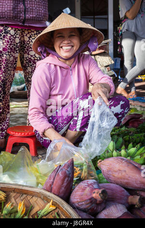 Nha Trang, Viêt Nam - Décembre 02, 2015 : Smiling woman in traditional vietnamese hat vente de fruits à la rue Market, Nha Trang, Vietnam sur Décembre Banque D'Images