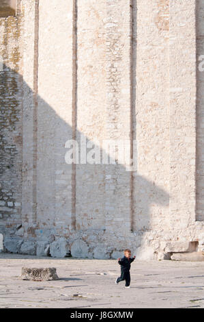 Un petit garçon jouant et en marche en face de l'église en Croatie Banque D'Images