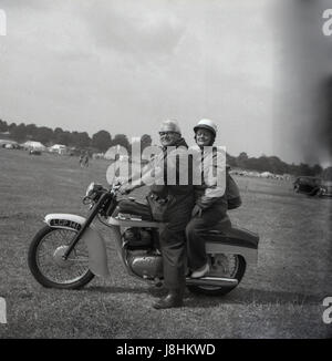 Angleterre, 1959, historique, moto, à l'extérieur dans un champ, un heureux couple âgé assis sur leur britannique a fait Norton moto, avec la femme assis sur le dos comme passager de pilolion. Banque D'Images