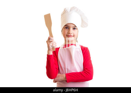 Peu de belle fille en chemise rouge avec tablier blanc et hat holding spatule de cuisine sur fond blanc en studio Banque D'Images