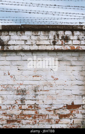 Fragment de mur de vieilles briques vieillies avec barbelés, le fond de ciel Banque D'Images