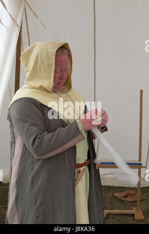 Femme habillée en costume traditionnel filant la laine dans la tente à réplique de l'ancienne colonie viking Banque D'Images