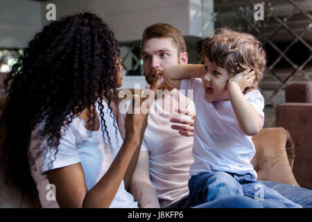 Beau couple est assis sur le canapé avec leur petit fils tout en ayant une querelle. Banque D'Images