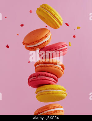 Différents types de macarons dans motion relevant sur fond rose. Doux et coloré qui tombent ou qui volent les macarons français en mouvement. Banque D'Images