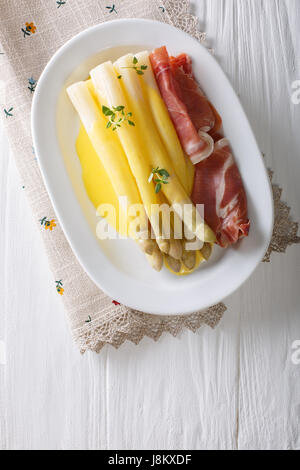 Les asperges blanches avec sauce hollandaise et de jambon sur une assiette. Vue verticale d'en haut Banque D'Images