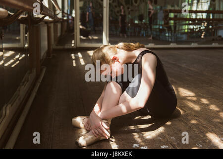 Jeune danseuse de ballet qui pratiquent en classe. Ballerine faisant des exercices. Girl s'étend même à la salle de danse. Banque D'Images