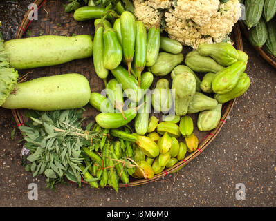 Légumes frais au panier en osier - le concombre, l'oignon, courge amère, les haricots verts, les courges, la salade, la carambole, le matin au marché chinois, Yangon, Myanmar Banque D'Images