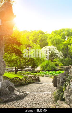 Quelques sentiers en gravier, pierres décoratives, lotus, buissons et arbres en Humble Administrator's Garden, Suzhou, province de Jiangsu, Chine. Jour d'été Banque D'Images