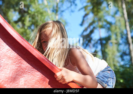 Les jeunes actifs enfant mignon girl in aire sur la diapositive sur une belle journée d'été. Activités d'été pour enfants. Banque D'Images