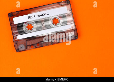 Retro cassette qui a le libellé 80's Music a écrit sur elle et un fond orange Banque D'Images