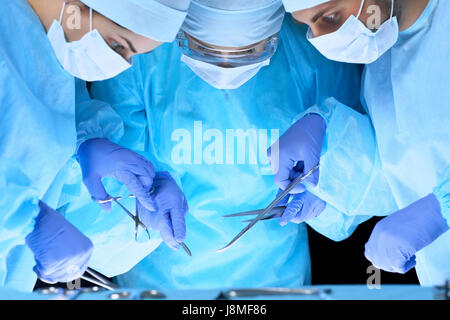 L'équipe médicale d'effectuer l'opération. Groupe de chirurgiens au travail en salle d'opération en bleu tonique Banque D'Images