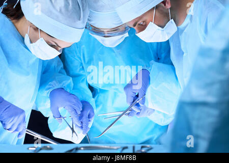 L'équipe médicale d'effectuer l'opération. Groupe de chirurgiens au travail en salle d'opération en bleu tonique Banque D'Images