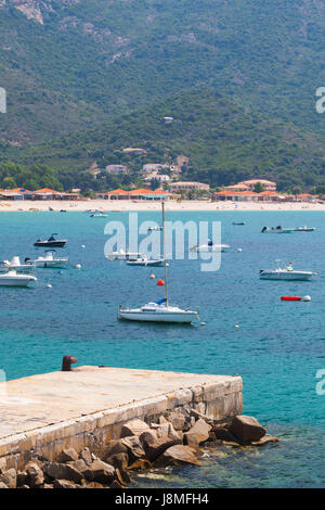 Plaisir des bateaux à moteur et yachts ancrés dans la baie d'azur près de la plage de sable des montagnes de l'île méditerranéenne de la Corse Banque D'Images