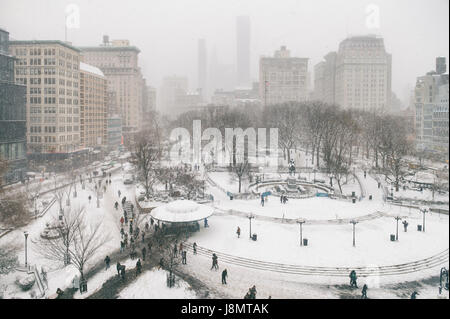Scène d'hiver enneigé avec des pistes laissées par les piétons dans la neige dans l'Union Square comme un blizzard dépasse New York City Banque D'Images