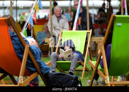 Hay Festival 2017 - Hay-on-Wye, au Pays de Galles, Royaume-Uni - Mai 2017 - Bank Holiday Hay un jeune garçon est assis et lit son Michael Morpurgo livre sur un mat sombre couvert de la banque lundi à l'Hay Festival - Steven Mai / Alamy Live News Banque D'Images