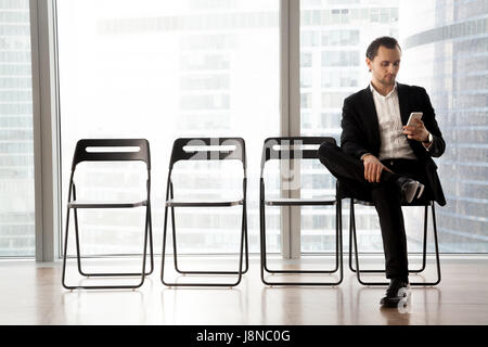 Avec l'homme en attente de cellulaire à son tour sur l'interview Banque D'Images