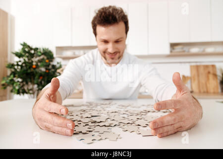 C'est la mienne. L'accent étant mis sur les mains d'un beau jeune homme assis à un comptoir de cuisine et déménagement jigsaw puzzle pieces plus près de lui Banque D'Images