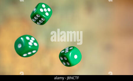 Plusieurs rolling green dice tombent sur une table avec jeu de société. Les moments de jeu. Close up. Banque D'Images