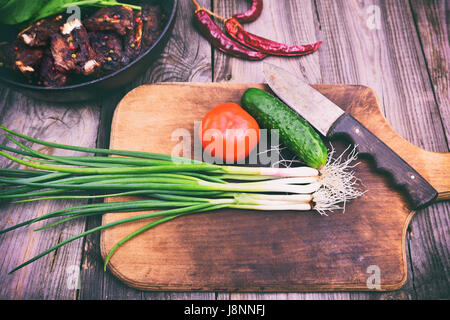 Les oignons verts et légumes frais sur une planche à découper en bois, vintage toning Banque D'Images