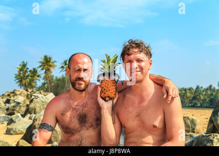 Deux hommes à l'ananas reste sur la plage. Le concept de vacances d'été. Banque D'Images