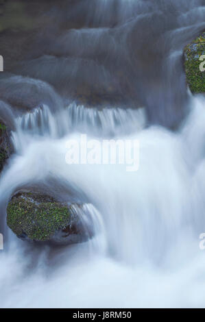 Close up of water Rushing River circulant sur les roches moussues Banque D'Images