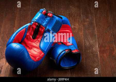 Paire de gants de boxe rouge et bleu se trouvant sur la table en bois brun. Banque D'Images