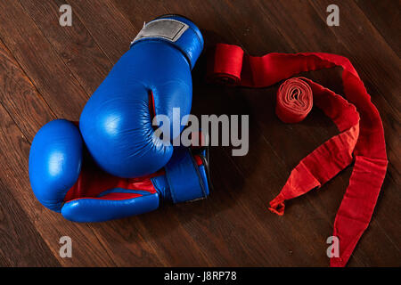 Vue de dessus le bleu et le rouge des gants de boxe et bandage sur planche en bois. Banque D'Images