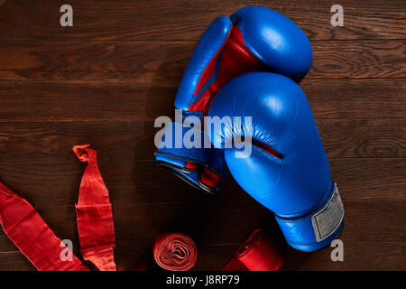 Vue de dessus le bleu et le rouge des gants de boxe et bandage sur planche en bois. Banque D'Images
