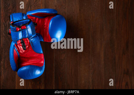 Paire de gants de boxe rouge et bleu se trouvant sur la table en bois brun. Banque D'Images