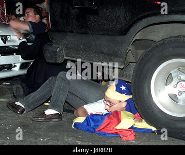 Les gens se cachent de coups tirés sous une voiture à Caracas, le 6 décembre 2002. Au moins un homme armé a ouvert le feu sur un carré emballé avec les adversaires de vénézuelien Banque D'Images