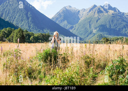 Femme photographe sur le terrain - Vallée d'Eglington Nouvelle-Zélande Banque D'Images