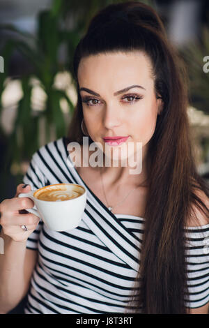 Portrait de la belle mais un peu fatigué femme tenant une tasse de Cappuccino. Banque D'Images