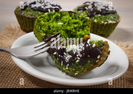 Muffin maison avec farine complète avec les épinards, noix de coco desséchée et lustre de chocolat, délicieux, dessert ou une collation saine Banque D'Images