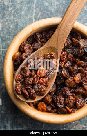 Raisins secs doux en cuillère en bois sur la vieille table de cuisine. Vue d'en haut. Banque D'Images