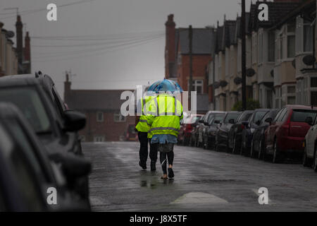 Couple en train de marcher sous la pluie au milieu de la route sur un après-midi très humide. Banque D'Images