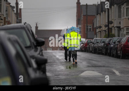 Couple en train de marcher sous la pluie au milieu de la route sur un après-midi très humide. Banque D'Images