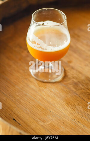 Verre de bière de blé debout sur un tonneau en bois dans une brasserie Banque D'Images