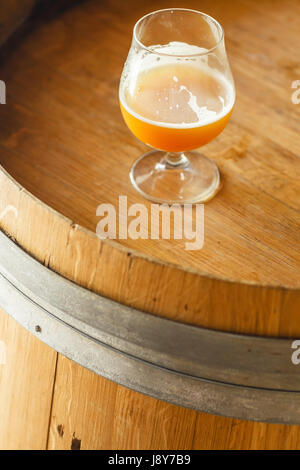 Verre de bière de blé debout sur un tonneau en bois dans une brasserie Banque D'Images