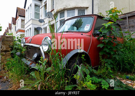 British Leyland Mini en décomposition rouillant dans une allée envahie côté rue à Westcliff sur Sea Essex. Avec disque fiscal. Original Mini Banque D'Images