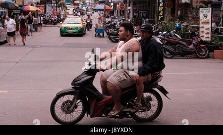 Gros homme conduisant une moto en circulation à soi et soi Buakhao Pattaya Thailande Diana Intersection la plus dangereuse sur un jour nuageux sombre Banque D'Images