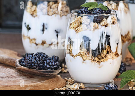 Les parfaits Blackberry fait avec du yaourt grec, granola et de mûres fraîches. L'extrême profondeur de champ avec selective focus on parfait dans foregrou Banque D'Images