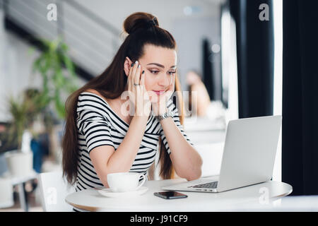 Jeune femme s'ennuie dans le bureau avec un ordinateur portable et à regarder l'écran d'ordinateur. Banque D'Images