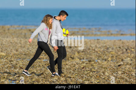 Jeune couple en tenant une soirée à pied le long de la plage, main dans la main. Banque D'Images