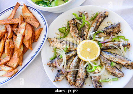 Des sardines grillées sur une plaque avec du citron et des pommes de terre sautées Banque D'Images