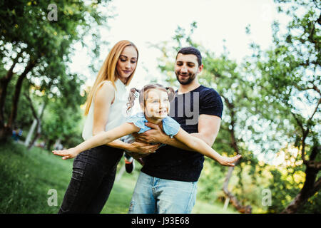 Joyeux Heureux jeune famille père, mère et fille s'amuser en plein air, jouer ensemble en parc d'été. Banque D'Images